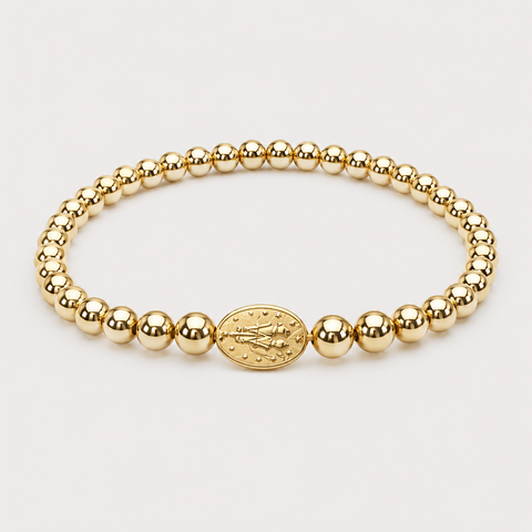 A gold beaded bracelet with a central oval religious medallion, displayed on a clean light gray background.