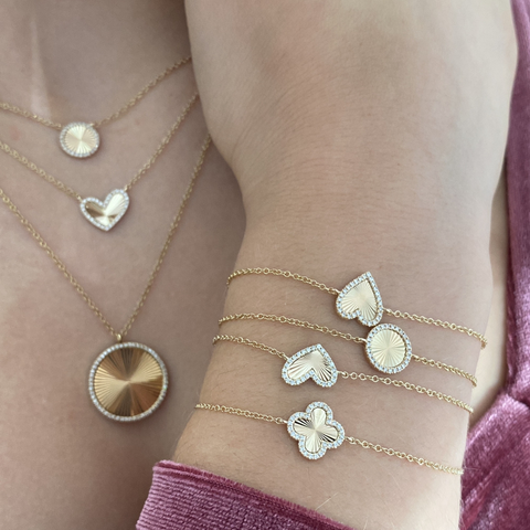 Model wearing different jewelry along with 14Kt Yellow Gold fluted disc pendant necklace with pavé diamond halo on adjustable gold chain.