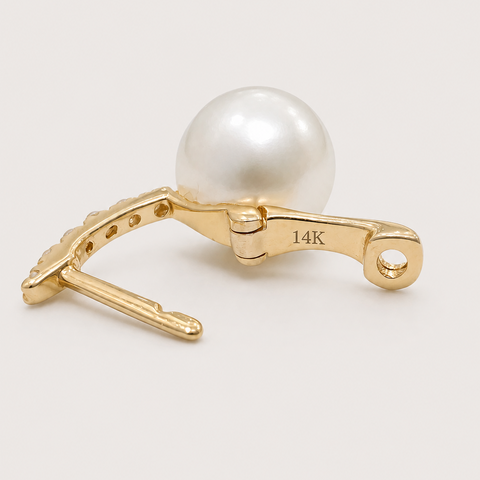 Close-up macro of 14K yellow gold pavé diamond huggie pearl drop earring showing 14K hallmark stamp on lever back clasp