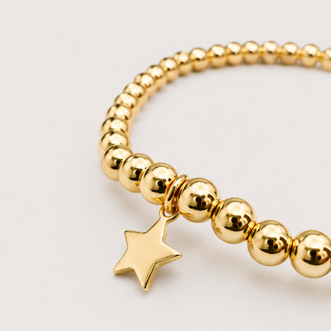 14K yellow gold ball bead stretch bracelet with solid polished star charm dangle, high polish finish, close-up angled view
