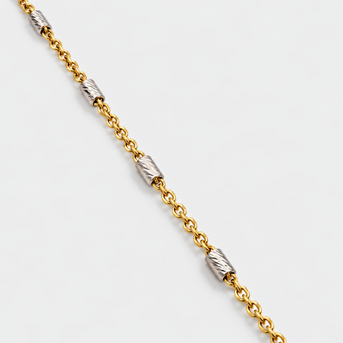 Close-up of the 18K two-tone gold necklace featuring diamond-cut white gold barrel stations and a fine yellow gold chain by Vaskia Jewelry.