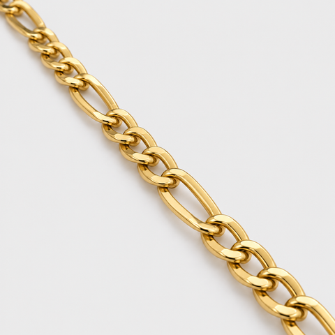 Close-up of the polished alternating Figaro links on an 18K yellow gold chain necklace.