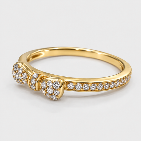 Angled view of an 18K yellow gold pavé diamond bow ring showing its diamond-set band.