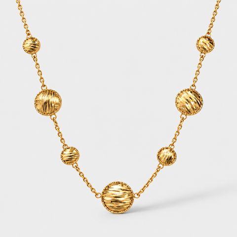 Front view of an 18K yellow gold station necklace with alternating large and small diamond-cut discs.