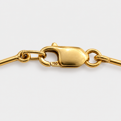 Close-up of the lobster clasp stamped 750 on an 18K yellow gold omega necklace.