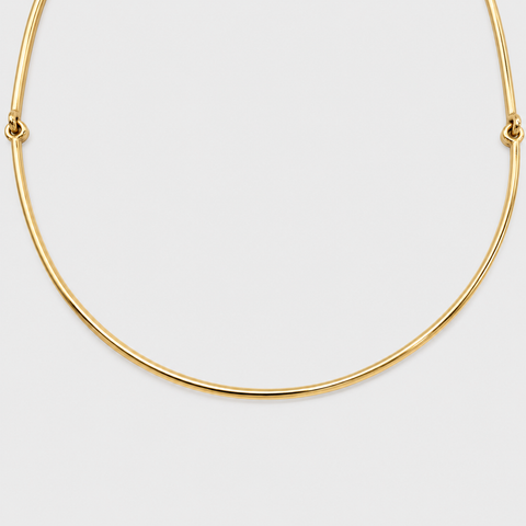 Detail of the smooth curved center of an 18K yellow gold omega necklace.