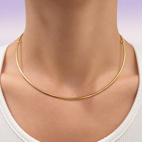 18K yellow gold omega necklace worn at the neckline with a white top.