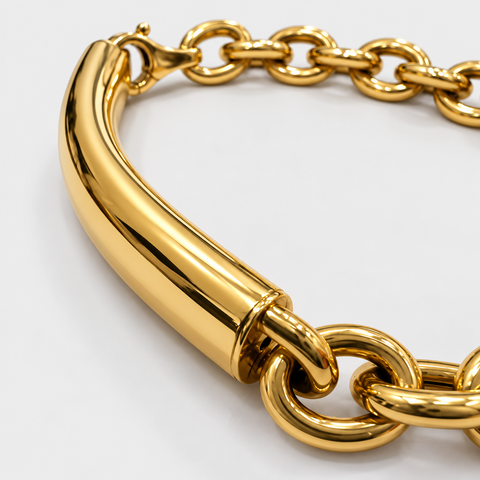 Close-up of the polished tubular bar and connecting rolo links on an 18K yellow gold bracelet.