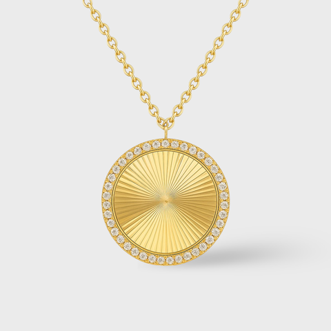 Gold necklace with a round pendant on a light gray background