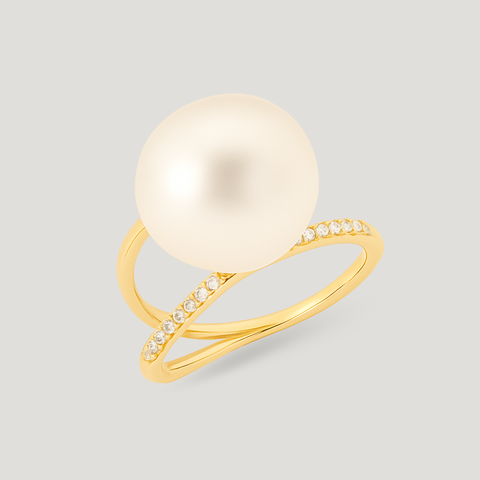 Gold ring with a large pearl and smaller stones on a light gray background