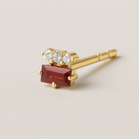 Three round diamonds on top of a baguette ruby piercing