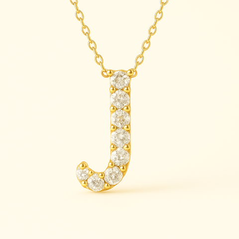 Close-up of 14K gold pavé diamond initial J pendant necklace with fine chain.