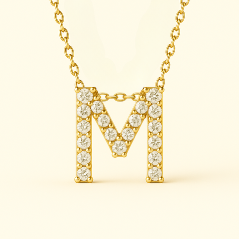 Close-up of 14K gold pavé diamond initial M pendant necklace with fine chain.