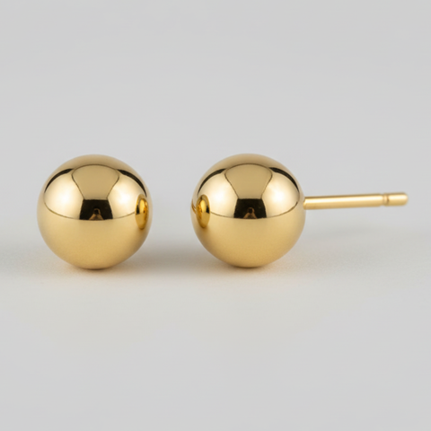 Pair of gold spherical earrings on a light gray background