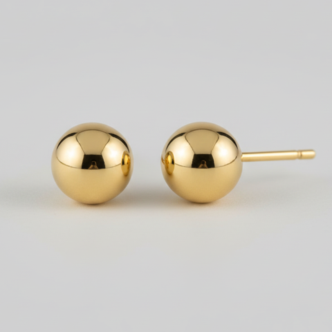 Pair of gold sphere earrings on a light gray background