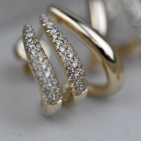 Gold hoop earrings with diamond accents on a light background